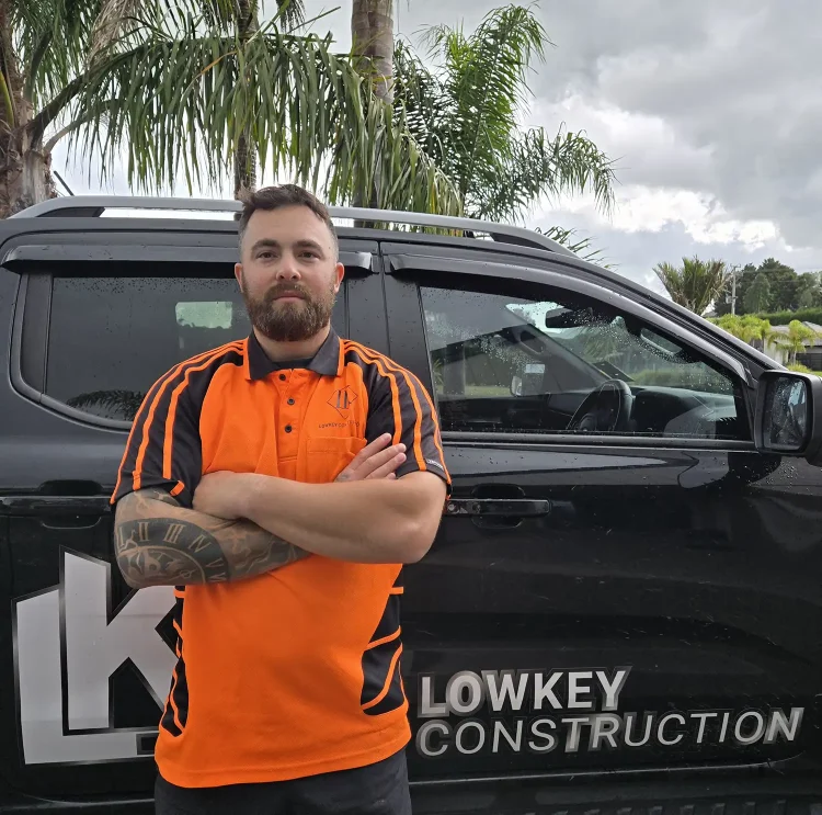 Logan Dobson, owner of Lowkey Construction, standing in front of a branded company vehicle in Whangarei.